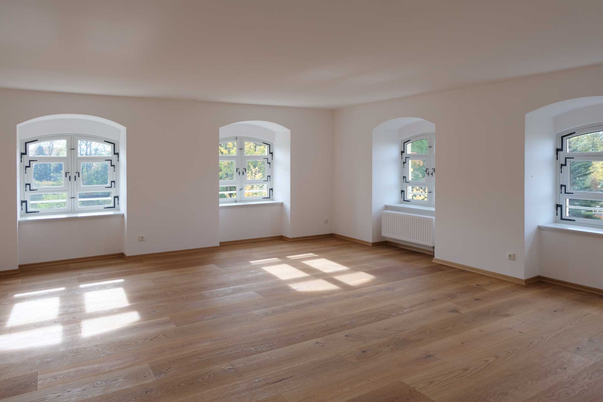 Barockschloss Wachau Blick in Zimmer einer DG-WE, 4 historische Rundbogenfenster, Parkettboden
